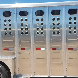 Standard hole punches with a large top oval and smaller circular punches below on the outer right side of a gooseneck trailer