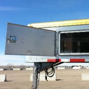 A smaller door on a gooseneck trailer's nose is pictured open to reveal the nose's interior.